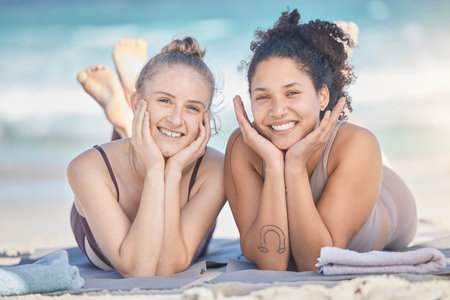 Friends, smile and beach happiness with women together on vacation, holiday and travel while lying on sand, bonding and enjoying freedom. Face portrait of lesbian couple outdoor at sea for summer funの写真素材