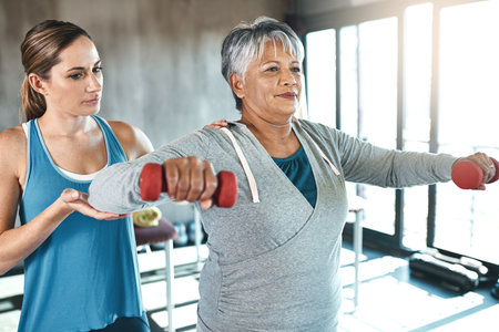 Live active, live well. a senior woman using weights with the help of a physical therapist.の写真素材