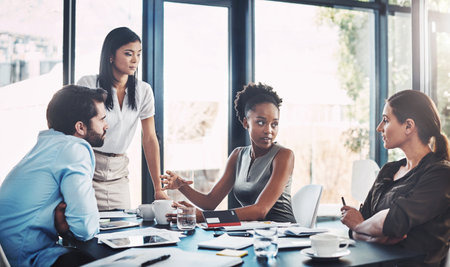 Making suggestions to her team. a group of diverse businesspeople having a meeting in the boardroom.の写真素材