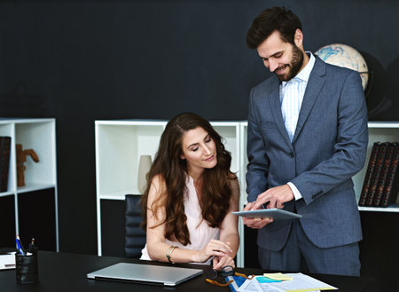 These business statistics are looking good so far. businesspeople working together on a digital tablet in a modern office.の写真素材