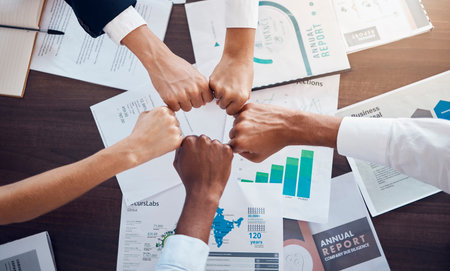 Hands, team and analytics in business meeting for collaboration, agreement or partnership at the office. Hand of employee group in fist bump for analysis strategy, teamwork or unity at the workplaceの写真素材