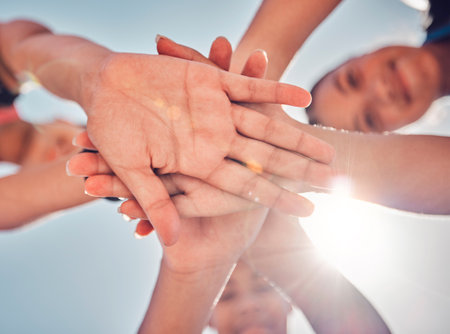 Hands, teamwork and collaboration of friends, community or people together for charity, support and motivation outdoor with lens flare. Group together for trust, commitment and synergy from belowの写真素材