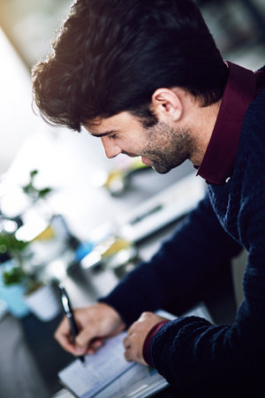 Scheduling his appointments. a young businessman working in the office.の写真素材