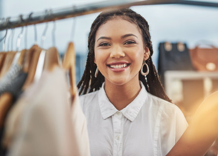 Shes always loved playing shop. Cropped portrait of a woman looking at clothes on a rail in a store.の写真素材