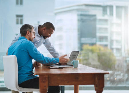 Mind taking a look. two businessmen working on a laptop in their office.の写真素材