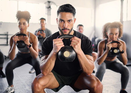 Kettlebell, workout and fitness class with a gym coach and people training with cardio and exercise. Portrait of a strong personal trainer and sports friends in a wellness health club with motivationの写真素材