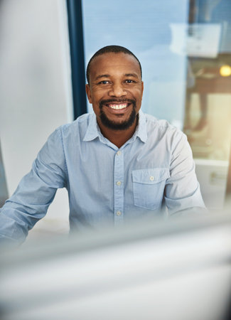 Its a fulfilling career. Cropped portrait of a businessman working on his computer in the office.の写真素材