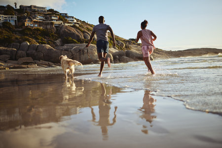 Running, fitness and dog with couple at beach and training for health, workout and exercise together. Love, freedom and wellness with man and woman runner with pet by the ocean for sports and summerの写真素材