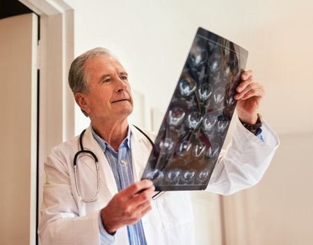 Radiology is his speciality. a mature doctor holding up an x-ray to examine it.の写真素材