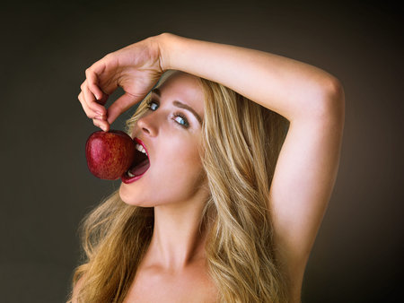Forbidden fruit tastes the sweetest. Studio shot of a gorgeous young woman eating a red apple...