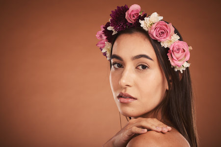 Face, beauty and flowers with a model woman in studio on a brown background with mockup to promote natural skincare. Wellness, portrait and luxury with an attractive young female wearing a wreathの写真素材