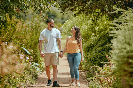 Couple, hand holding and nature park walking of people on a outdoor path with a smile. Happy girlfriend and boyfriend together showing love, care and commitment on a walk or hike feeling happinessの写真素材