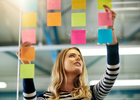 Putting priorities into perspective. a young woman having a brainstorming session with sticky notes...