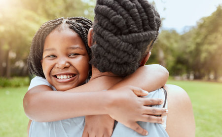 Family, children and hugging with a mother and daughter in a nature park or garden while spending time together. Summer, portrait and love with a girl and black woman embracing while bonding outdoorの写真素材