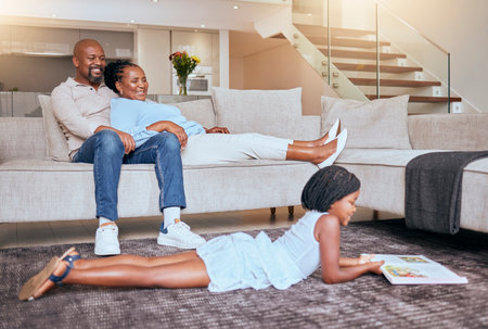 Black family, relax and child reading a book or fantasy story for children entertainment in house living room. Smile, mother and happy father relaxing on sofa with an African girl learning in Kenyaの写真素材
