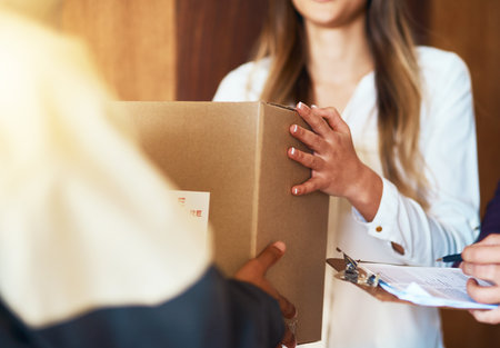 Straight to your door and safely within your hands. Closeup shot of a courier making a delivery to a woman.の写真素材