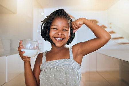 Milk, portrait and African girl with muscle from healthy drink for energy, growth and nutrition in the kitchen. Happy, smile and child flexing muscles from calcium in a glass and care for healthの写真素材