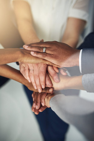 Teamwork makes all the difference in performance. a team of colleagues joining their hands together...