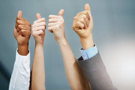 The thumbs of approval. a group of businesspeoples hands showing thumbs up in the office.の写真素材