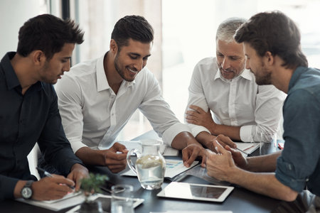 These guys know their business. a group of businessmen having a meeting around a table in an office.の写真素材