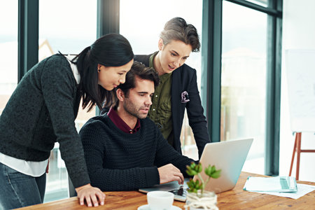 Wow, youve really worked hard on this. a team of businesspeople discussing work at a desk in their...