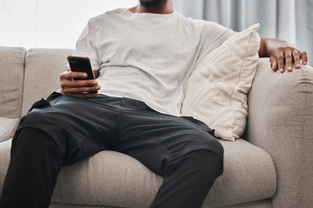 Social media, relax and man on the sofa with a phone for communication, internet and mobile app chat. Website, connection and person on the couch with a mobile, wifi and search of the web in his homeの写真素材