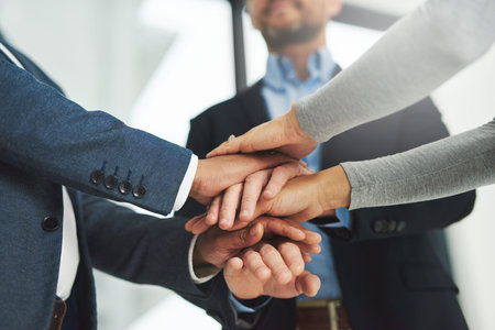 We can achieve anything with teamwork. a team of colleagues joining their hands together in unity.
