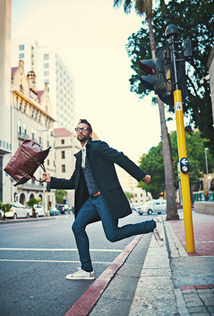 Know what you want and go get it. a stylish man rushing to cross a city street.の写真素材