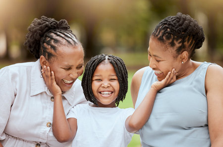 Mother, grandmother and child in garden, happy family sitting on grass, generations at picnic in park. Black family, women and small girl in nature together with love and support from mom and grandmaの写真素材