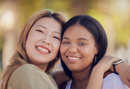 Friends, hug and love outdoor in nature park for fun, support and bonding outdoor with a smile, happiness and trust. Face portrait of asian and black woman lesbian, couple outdoor for travel and funの写真素材