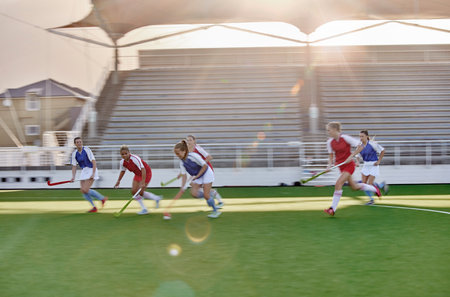 Women, hockey and sports on grass field, turf and pitch for competition, games and team training in outdoor sunshine. Girls field hockey players contest, action and performance match in stadium arenaの写真素材