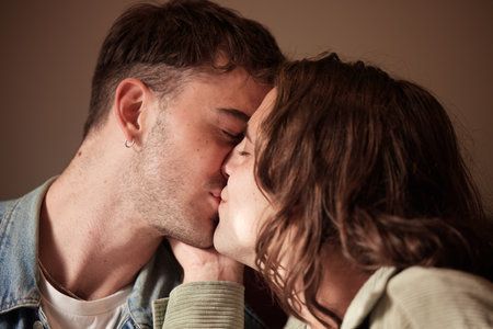 Couple kiss, love or gay men for trust, romance or support in studio with brown background. Happy, relax or LGBT people kissing for homosexual care, happiness or marriage anniversary dateの写真素材