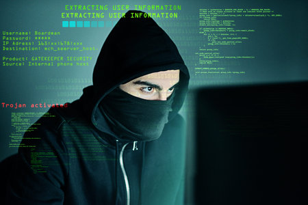 Theres no code he cant crack. a computer hacker using a laptop while standing against a dark...