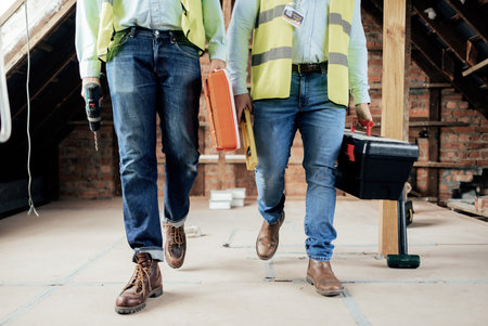 Construction, team and legs of engineers walking on the building site for home renovation project. People, construction worker teamwork and feet of men walking in industrial building for maintenanceの写真素材