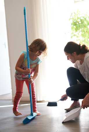 Turning housework into teamwork. a mother and daughter sweeping the floor together.の写真素材