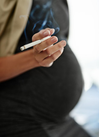 Harming more than herself. a woman smoking a cigarette while preganant.の写真素材