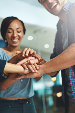 We work together, we win together. a group of colleagues joining their hands together in unity.