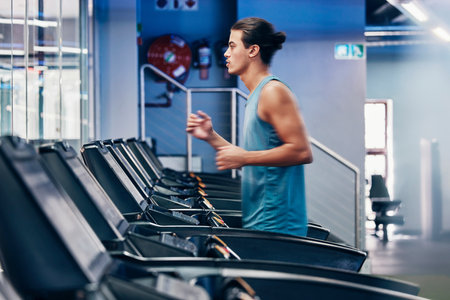 Treadmill, running and profile of man in gym for cardio workout and heart health. Fitness, sports and male runner on machine practicing for marathon, race or training for wellness in fitness center.の写真素材