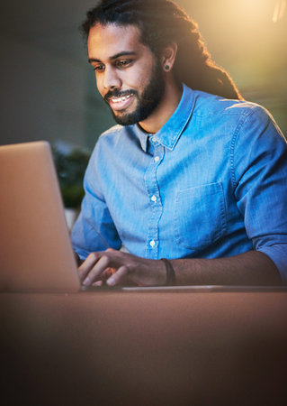 He always performs at his peak no matter the hour. a young designer working late on a laptop in an...