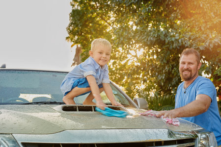 We clean as a team. Portrait of a father and son washing a car together.の写真素材