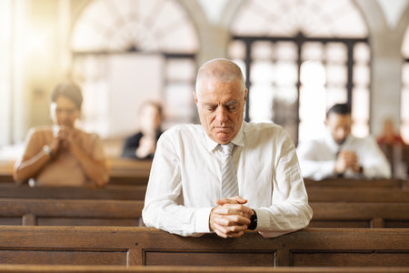 Praying, faith and in church to worship, spiritual and religion with believers, congregation and silent. Religious, connect and hands together for gratitude, closed eyes and prayer in tabernacle.の写真素材