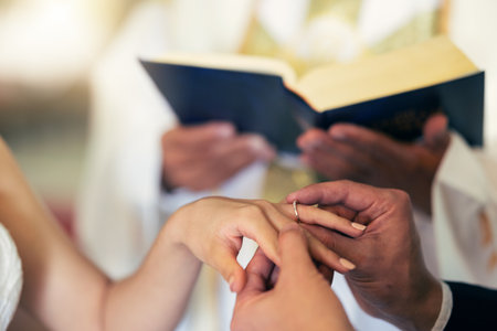 Couple hands with ring, wedding and marriage in church with priest and bible in traditional ceremony. Commitment, love and jewelry, man and woman together with trust and jewellery with bride.の写真素材
