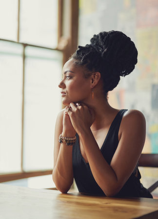 Shes got a permanent window seat in her local coffee shop. an attractive young woman sitting in a coffee shop.の写真素材