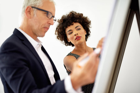 Proper planning to crucial to success. two colleagues brainstorming on a whiteboard in an office.