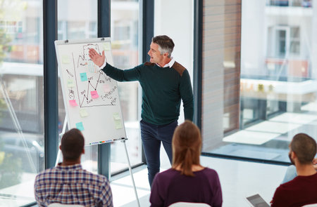 If youll focus your attention here...a mature businessman giving a presentation in the boardroom.
