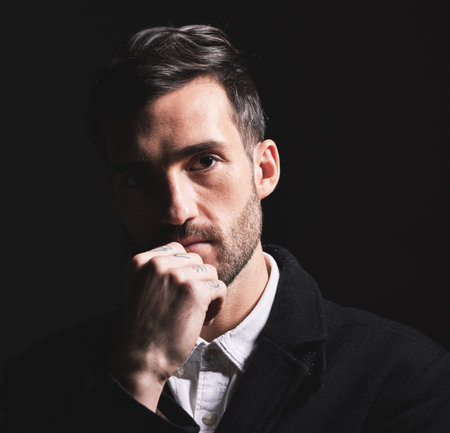 Man, idea and thinking face, fashion and portrait against a black studio background with mockup space. Male model, style and elegant clothes, young or confidence with beard, attractive or fashionableの写真素材