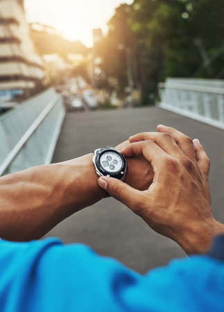 Trying to beat his personal best. a runner checking his sports watch while training.の写真素材