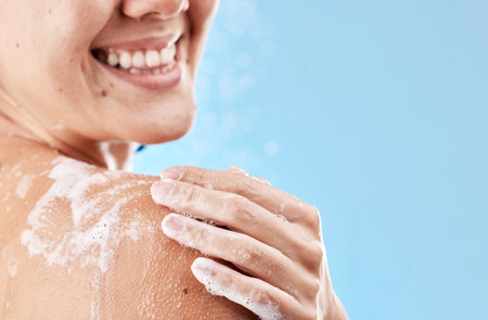 Shower, soap and smile of a woman grooming body for health, skincare and wellness against a blue...