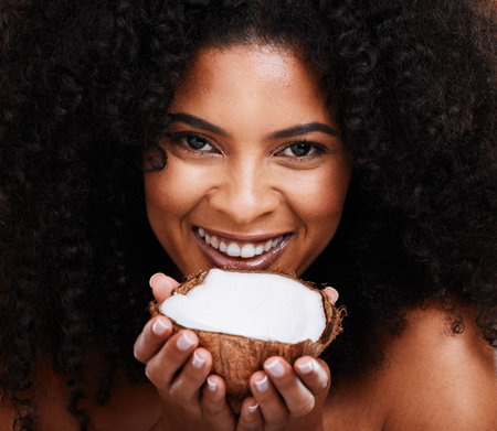 Beauty, portrait and woman holding coconut for organic skincare, bodycare and glowing skin. African american female, body care and skin care with fruit for natural cosmetology productの写真素材