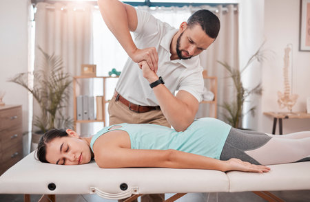 Chiropractor, massage and physiotherapy treatment for back muscle with a woman patient. Consulting healthcare, wellness and chiropractic employee in a clinic helping with healthy body balanceの写真素材